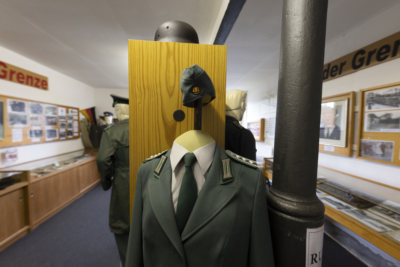 Ausstellungsraum mit Schaukästen und Fotos an den Wänden. In der Mitte eine Puppe mit einer Uniform.