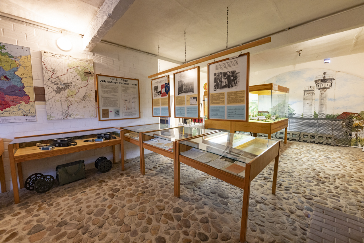 Schaukästen mit Dokumenten und Objekten in einer Ausstellung. Im Hintergrund ein Modell und eine Zeichnung von Grenztürmen.