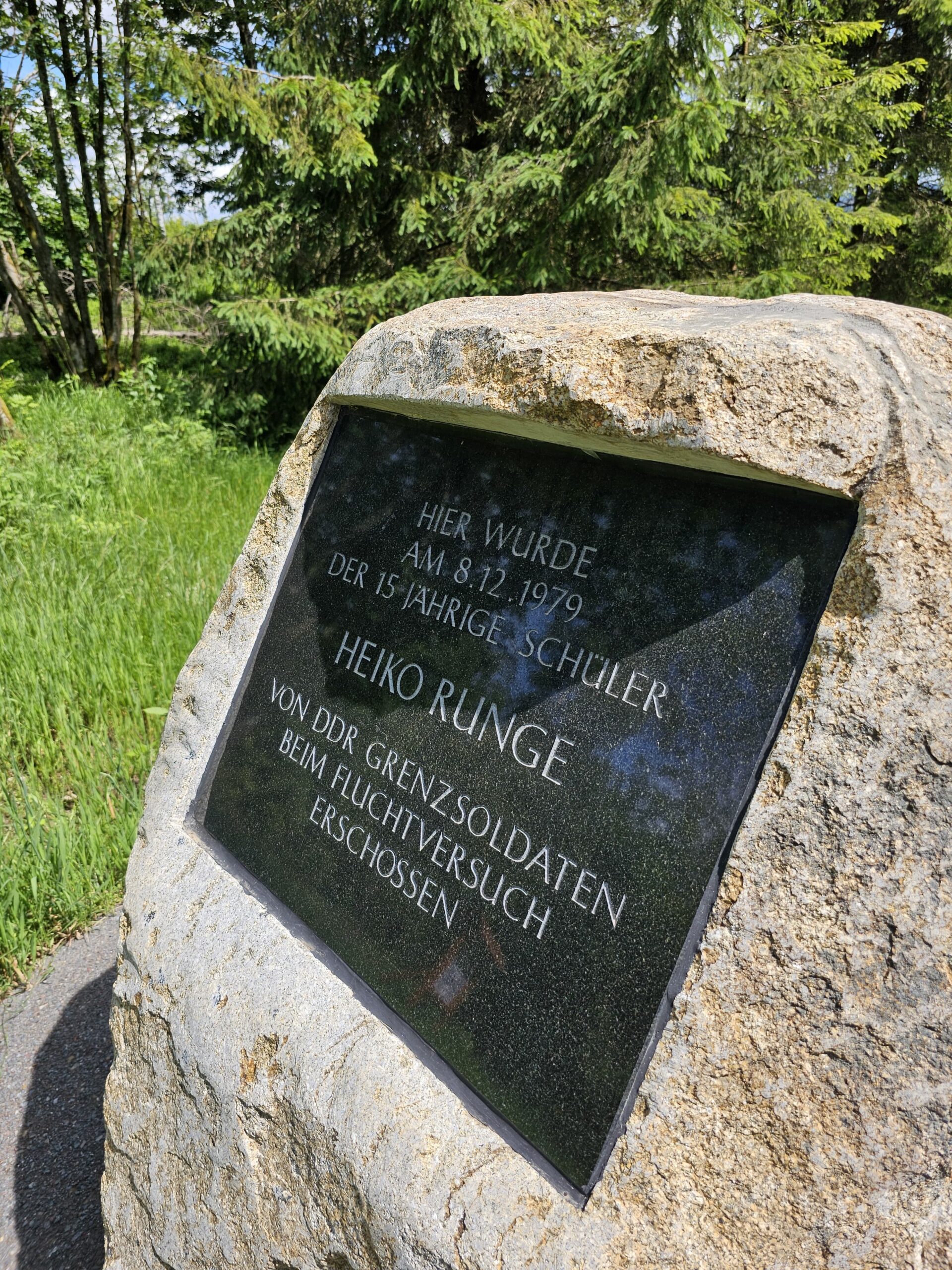 Ein heller, großer Stein mit einer schwarzen Platte darin. Darauf der Text: Hier wurde am 8.12.1979 der 15-jährige Schüler Heiko Runge von DDR Grenzsoldaten beim Fluchtversuch erschossen. Im Hintergrund grüne Bäume und Wiese.